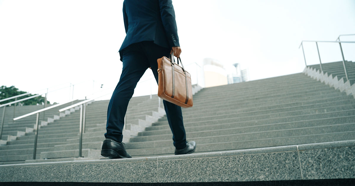 A professional financial advisor climbing a set of stairs, symbolizing taking the first step toward achieving success in 2025.