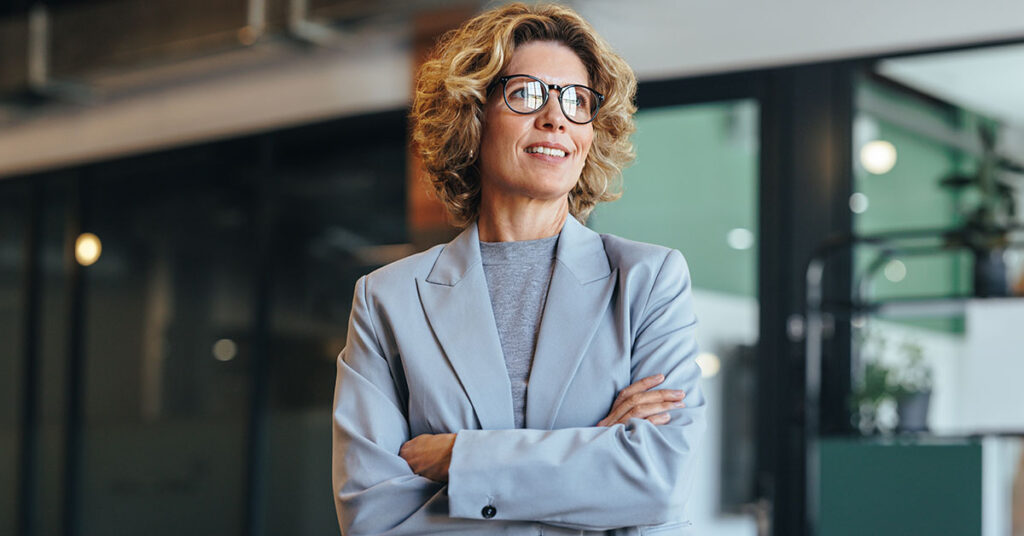 Confident businesswoman standing with folded arms, representing success and expertise as a financial advisor.