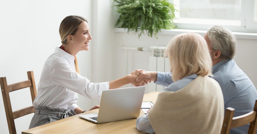 A smiling financial advisor welcomes an older couple with a handshake, illustrating how Financial Gravity’s solutions help advisors build trust from the very first hello.