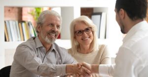 Blogs 11 A happy senior couple shakes hands with a financial advisor in an office setting, symbolizing trust and successful financial planning with Financial Gravity.