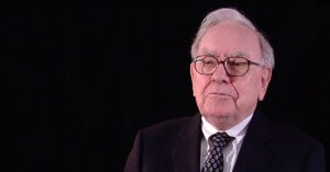 Blogs 8 Warren Buffett in a suit and tie, seated against a black background, reflecting on investing principles—anchoring the message of Financial Gravity’s market guidance.
