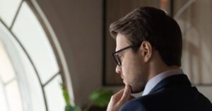 Blogs 4 Financial advisor in deep thought near a large window, reflecting the risk of ignoring client feedback—solved with Financial Gravity’s systems.