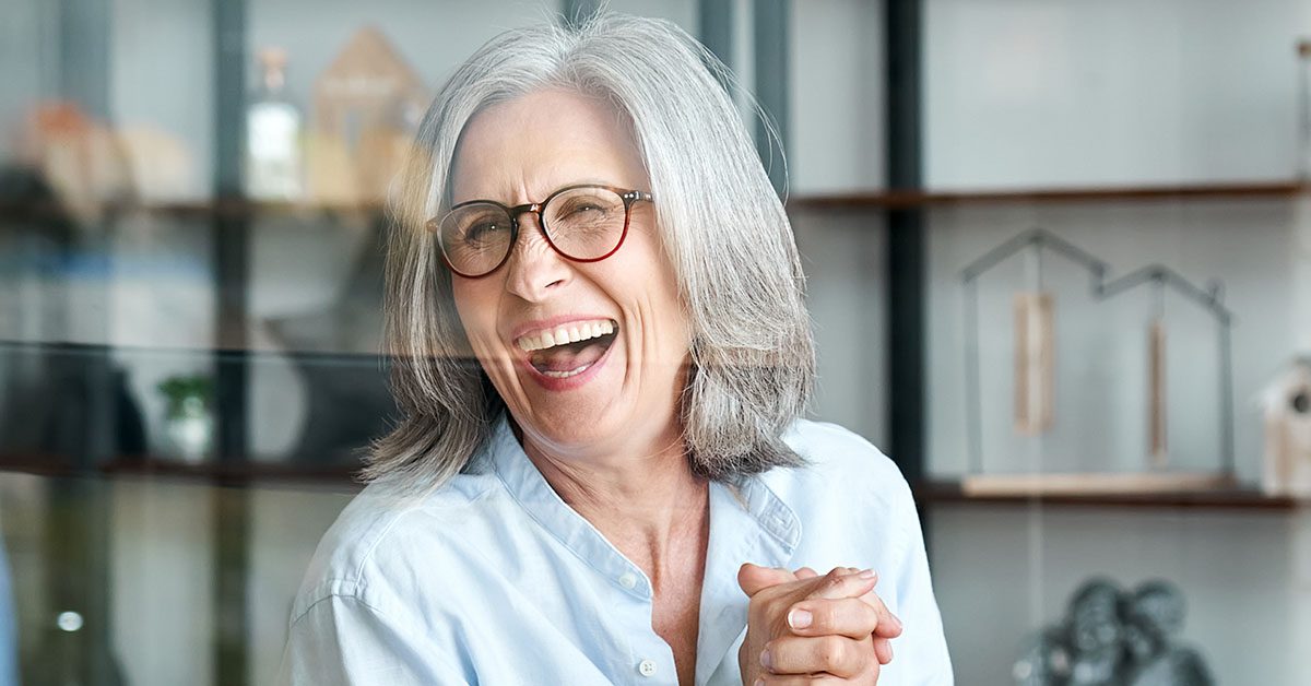Confident older woman laughing joyfully in a bright, modern setting, symbolizing the fulfillment and peace of mind that comes from knowing your business is truly valued.