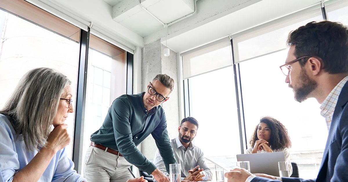 Financial advisor leading a focused strategy discussion with a diverse team in a modern office, symbolizing the evolution to a multi-family office model.