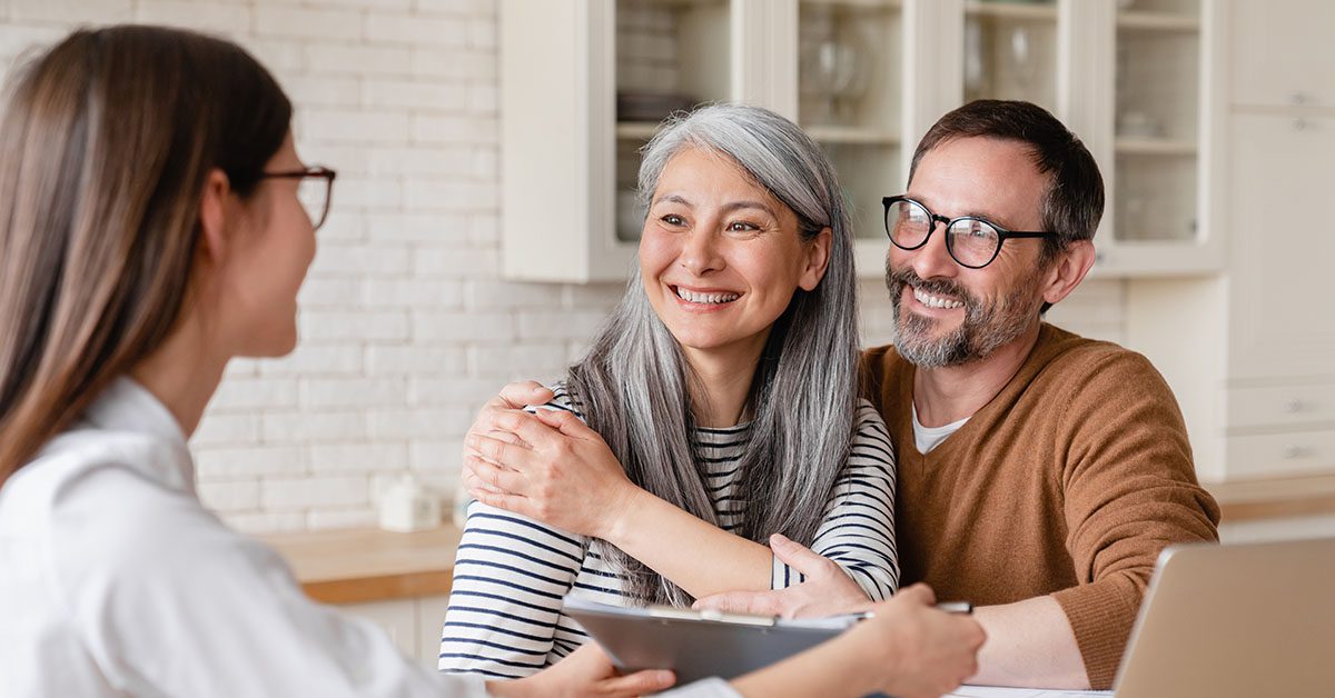 A financial advisor meets with a smiling couple at home, reflecting how Financial Gravity supports advisors in building trusted, human connections that no AI can replace.