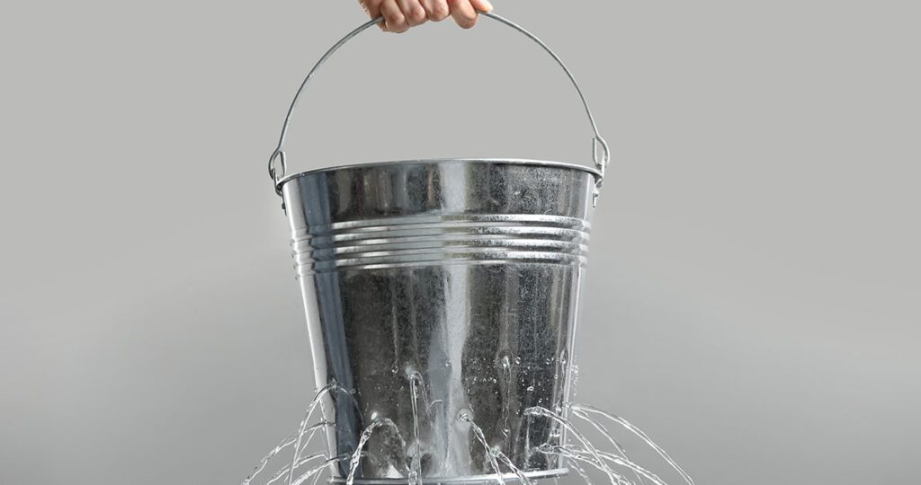 A leaking metal bucket representing how inefficiency drains value from advisory firms and how Financial Gravity’s Turnkey Multi-Family Office Charter helps advisors plug the leaks and scale efficiently.