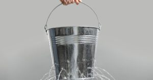 A leaking metal bucket representing how inefficiency drains value from advisory firms and how Financial Gravity’s Turnkey Multi-Family Office Charter helps advisors plug the leaks and scale efficiently.