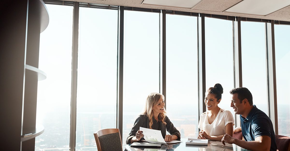 A financial advisor meets with clients in a bright, modern office, reviewing documents that highlight measurable value and strategic planning outcomes.
