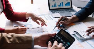 Financial Gravity coordinates specialists for financial advisors, shown by professionals collaborating over charts with a laptop and calculator.