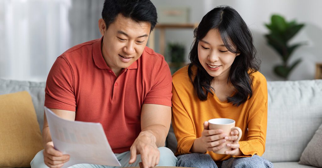 A couple reviews financial documents together at home, discussing decisions and shared priorities around their wealth.