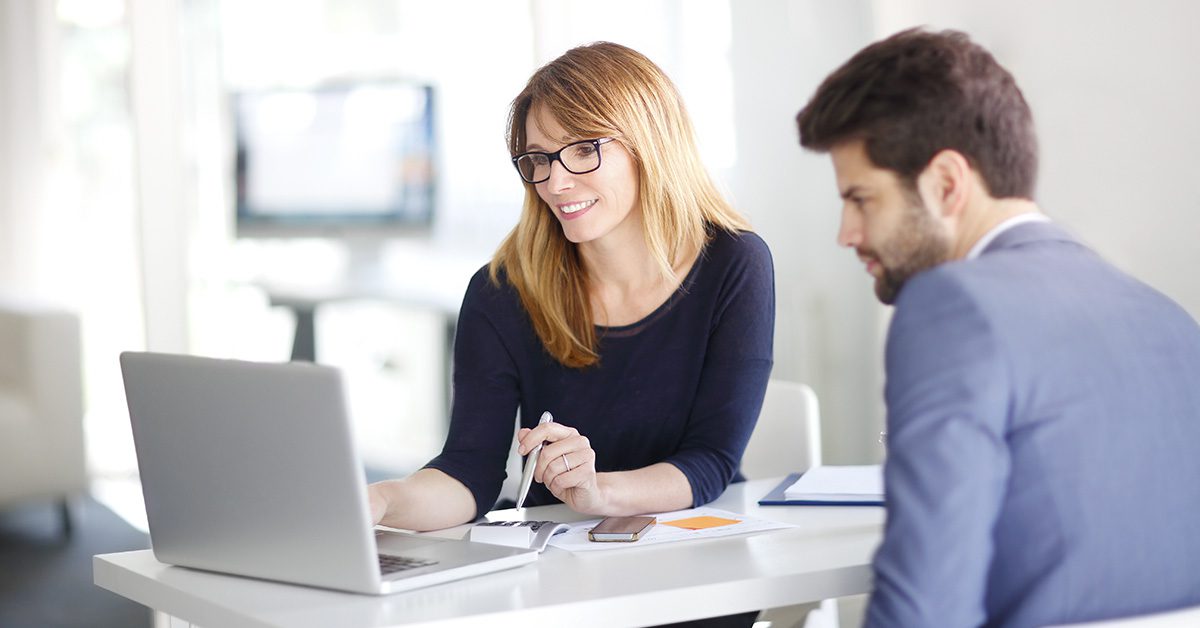 A financial advisor reviews integrated planning information with a client using a laptop in a modern office setting.