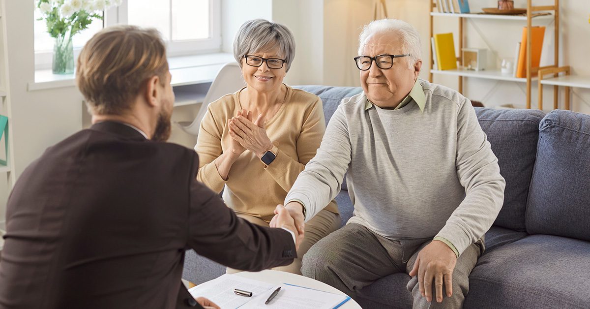 Financial Gravity helps financial advisors build trust, shown by a couple happily sealing an agreement with their financial advisor at home.