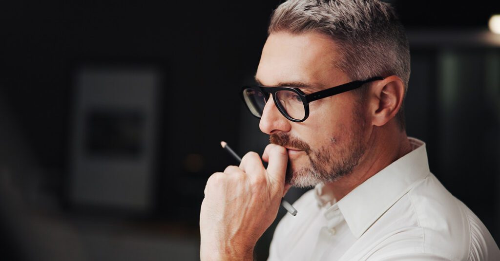 A focused financial advisor pauses to think through priorities, pencil in hand, before committing time on the calendar.