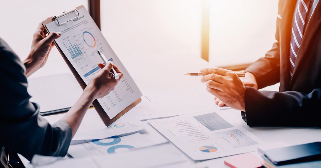 A financial advisor reviews detailed financial charts and reports with a client during a strategy discussion.