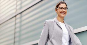 A confident financial advisor walks outside a modern office building, focused and prepared for the day ahead.