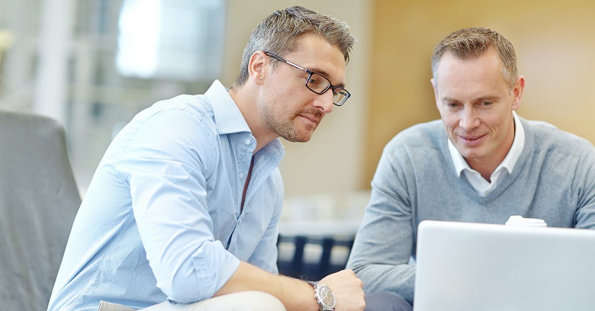 A financial advisor reviews information with a client on a laptop during a focused, collaborative meeting.
